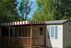 A small, single-story cabin with a porch, a covered area with striped awning, and a sign that reads 'O'Phée.'