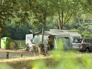 Ein Campingplatz mit Zelt, Überdachung und einem Auto.