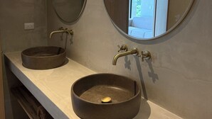 A bathroom with two round sinks, each with a round mirror above. There is a towel rack to the left of the sinks.