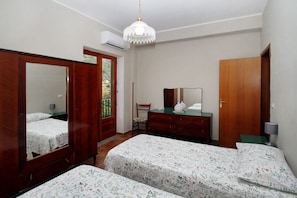 Quarto com duas camas, penteadeira, espelho e lustre.