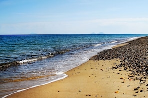 Una playa con orilla pedregosa y mar tranquilo.