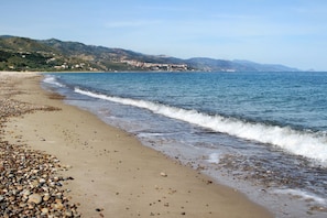 Uma praia com pedras e vista para colinas distantes.