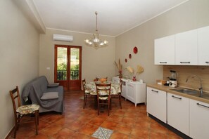 A compact kitchen with a dining area, white cabinets, a tiled floor, and a ceiling fan. - Il Giardino al Mare di Anna is an apartment located on the third and top floor of an old manor house, surrounded by the countryside of the Piana di Caronia and just a few steps from the sea.The apartment features a spacious kitchen-living area with a sof (Marina di Caronia)
