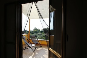 Varanda com duas poltronas de descanso e um toldo branco.