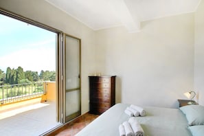 Un dormitorio con cama, cómoda y balcón con vistas a árboles.