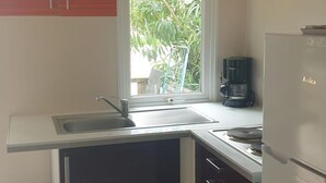 Et lille køkken med vindue, vask og kaffemaskine.