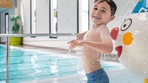Un enfant joue dans une piscine avec un ballon rempli d’eau.