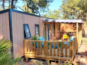 Une petite cabane en bois avec une terrasse, une porte et une fenêtre.
