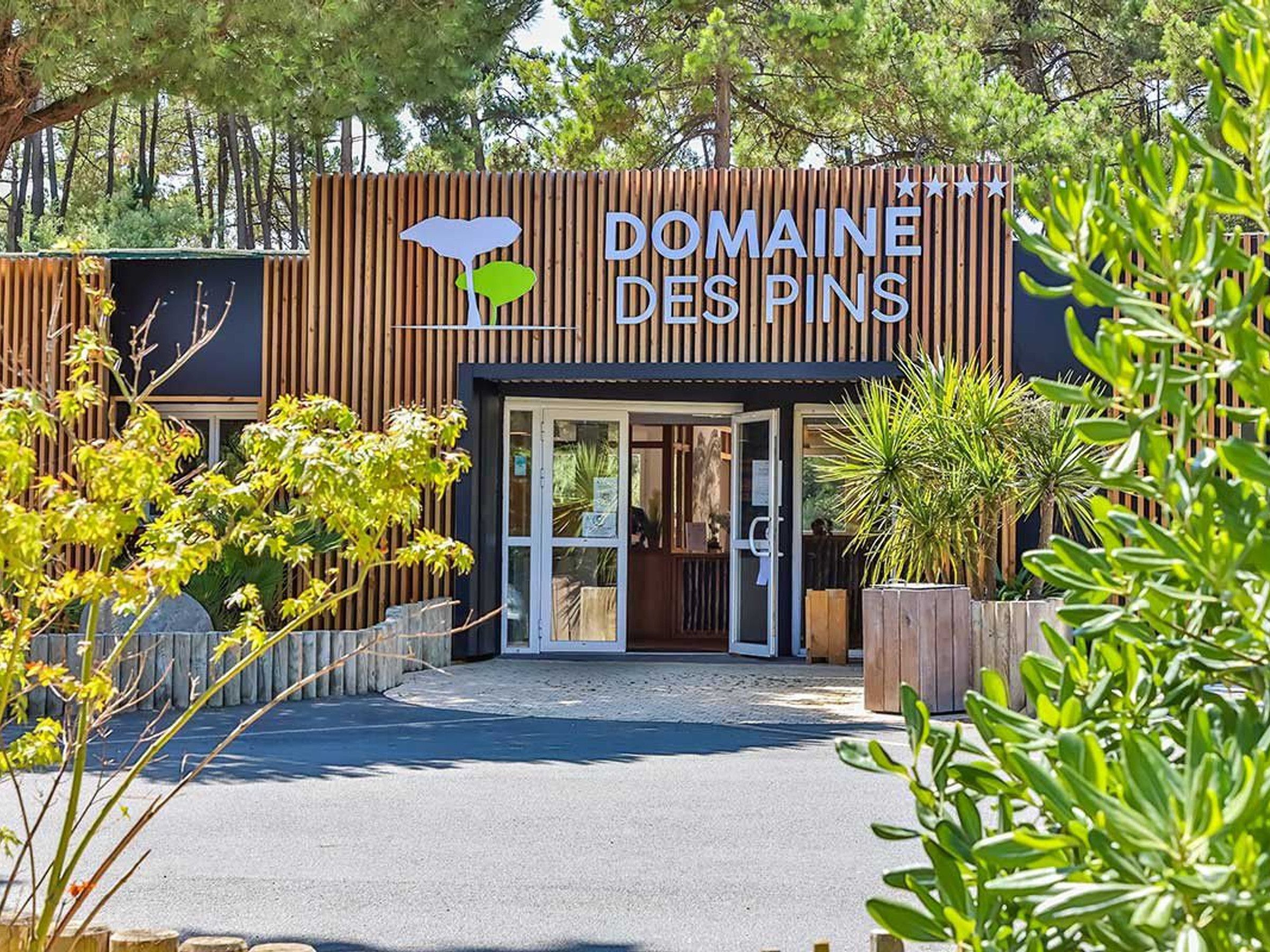 A hotel entrance with a wooden facade and a sign that reads 'Domaine des Pins'.