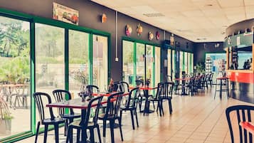 A restaurant with indoor seating, large windows, and a counter area.