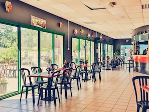 Un restaurant avec une salle à manger intérieure, de grandes fenêtres et un comptoir.