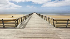 Una passerella di legno che conduce a una spiaggia sotto un cielo sereno.