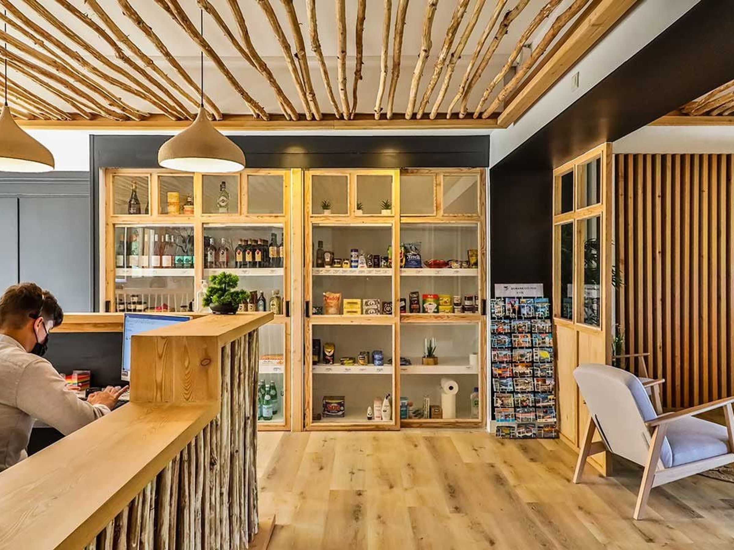 Una zona de recepción con un mostrador de madera, un espacio de descanso con una silla y una estantería con diversos objetos.