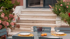 Un coin repas avec une table dressée pour deux personnes, une carafe et des oranges.
