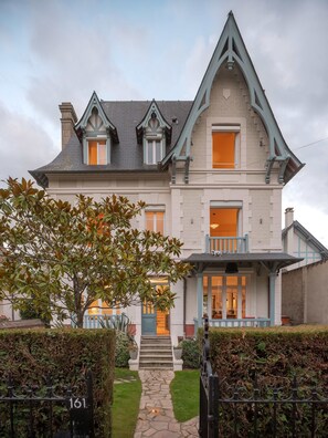 A Victorian-style house with a steeply pitched roof, dormer windows, and a stone entrance. - Large Chic Stylish Villa Superb Garden (Deauville)