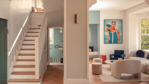 A spacious living area with a wooden staircase, a large painting, and a cozy seating arrangement. - Villa des Reves Luxury in Villers Pool Jacuzzi Padel Court Close to Deauville (Villers-sur-Mer)