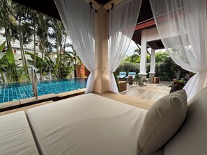 A poolside area with a glass-tiled pool, white curtains, and lounge chairs. - Villa Amida • Balinese Pool Villa • Big Sala & Terrace • Nai Harn & Rawai Beach (Tambon Rawai)