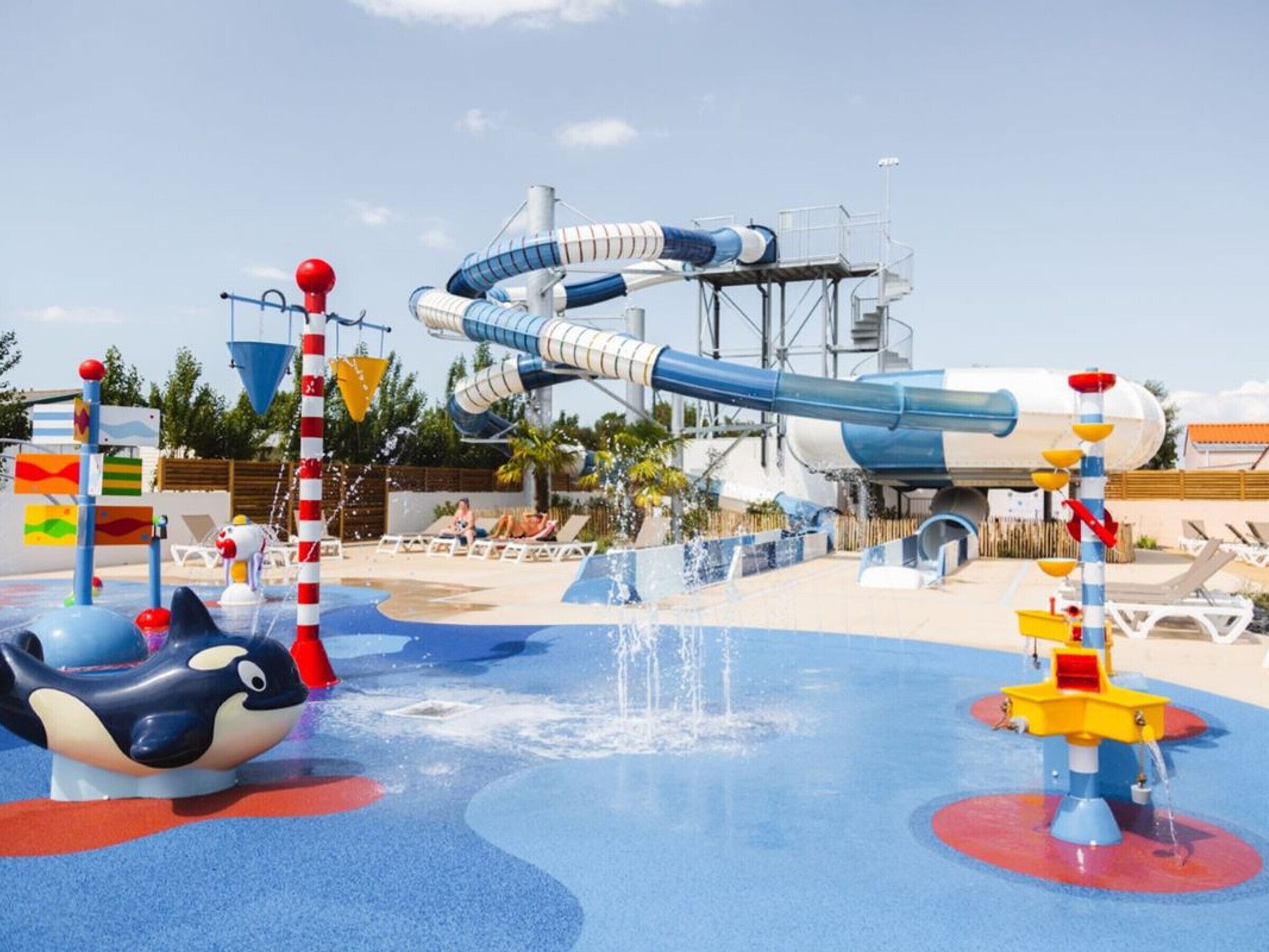 Un parque acuático con un tobog án de agua grande, una piscina de olas y diversas atracciones acuáticas.