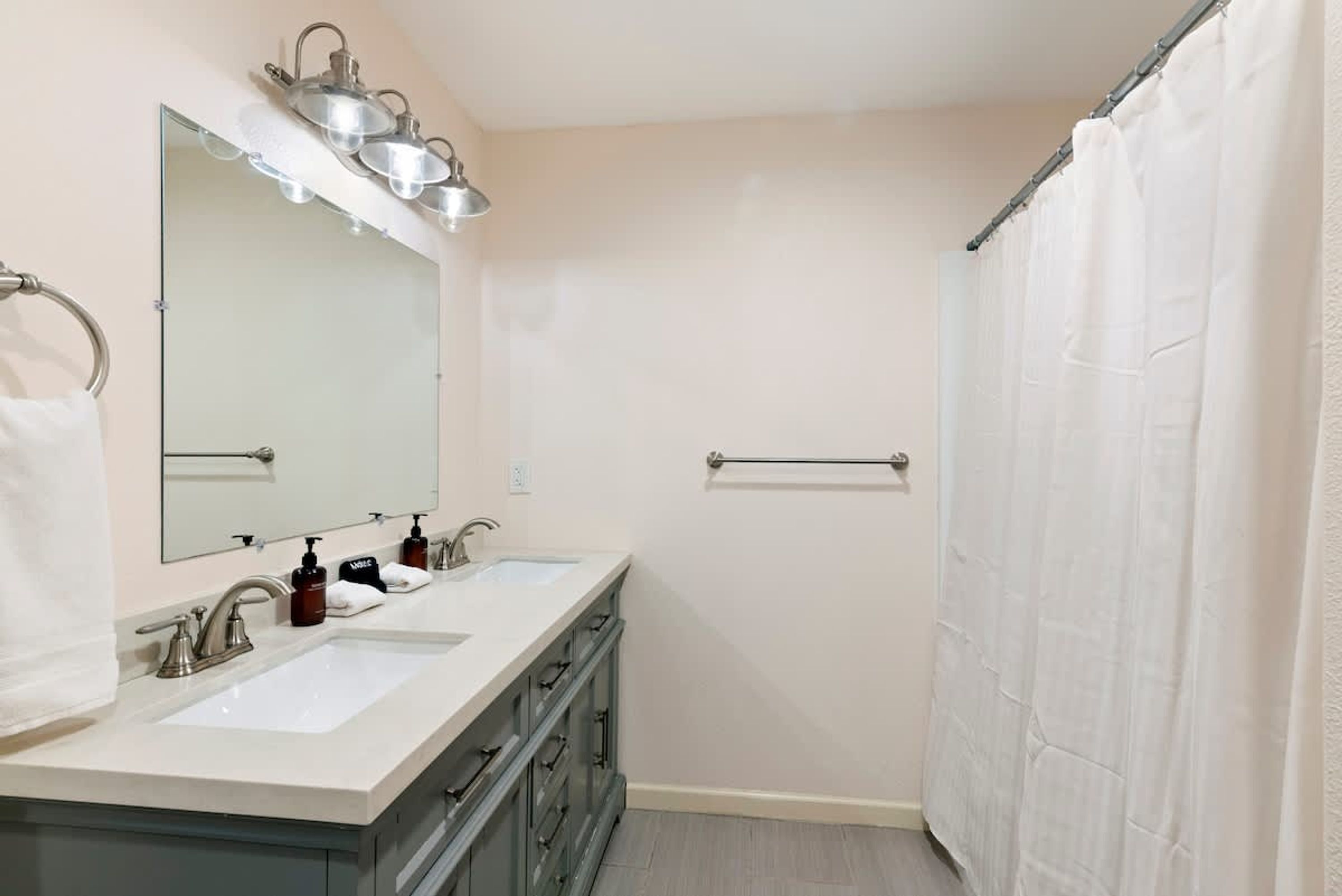 Baño con dos lavamanos, un espejo y cortina de ducha.