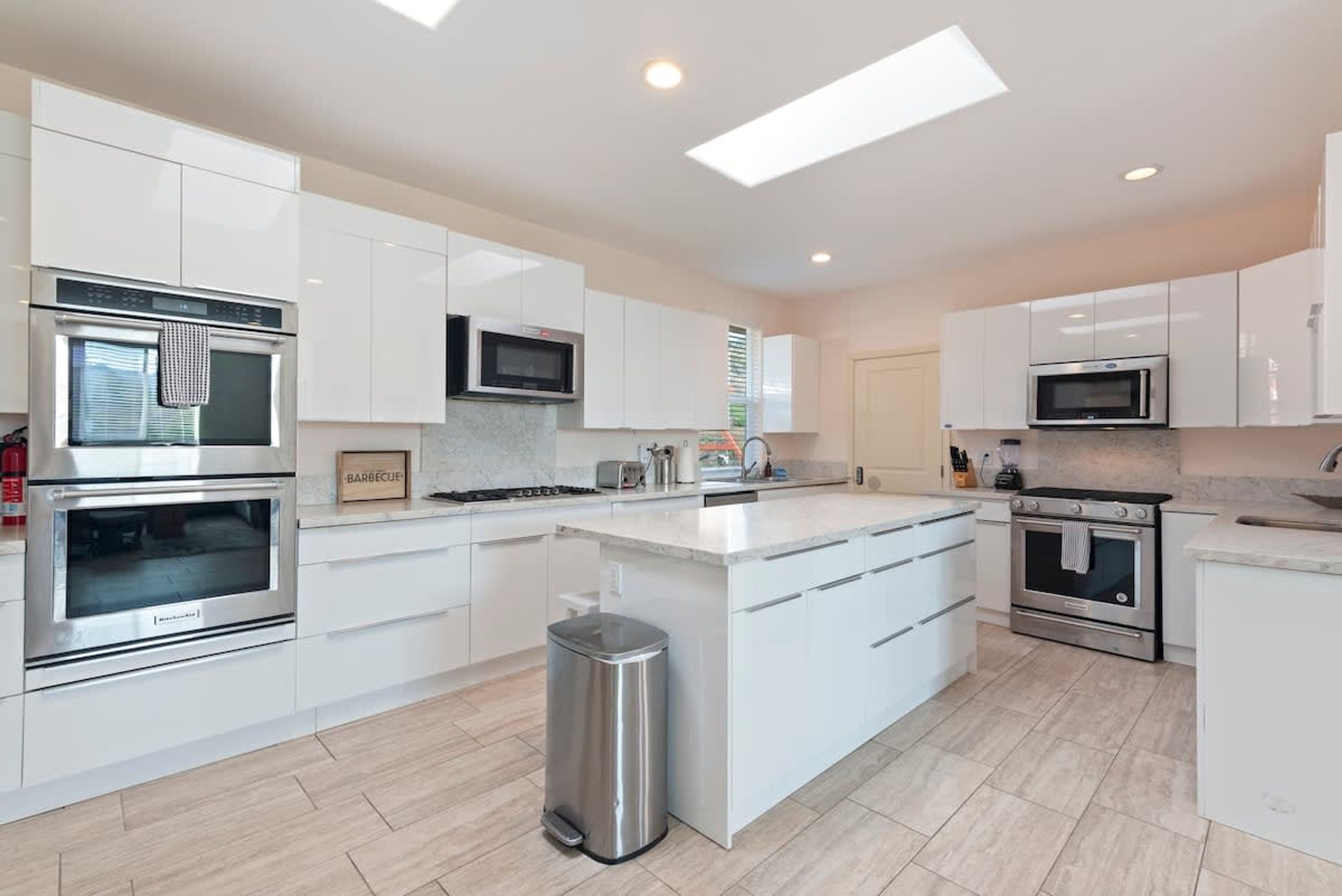 A modern kitchen with white cabinetry, stainless steel appliances, and a central island.