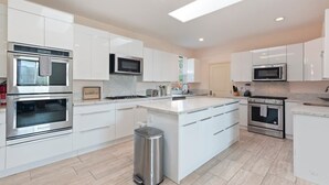 A modern kitchen with white cabinetry, stainless steel appliances, and a central island. - Spacious Single Level Home In Poway (Poway)