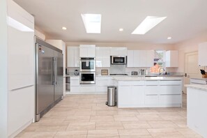 A modern kitchen with white cabinetry, stainless steel appliances, and a central island. - Spacious Single Level Home In Poway (Poway)
