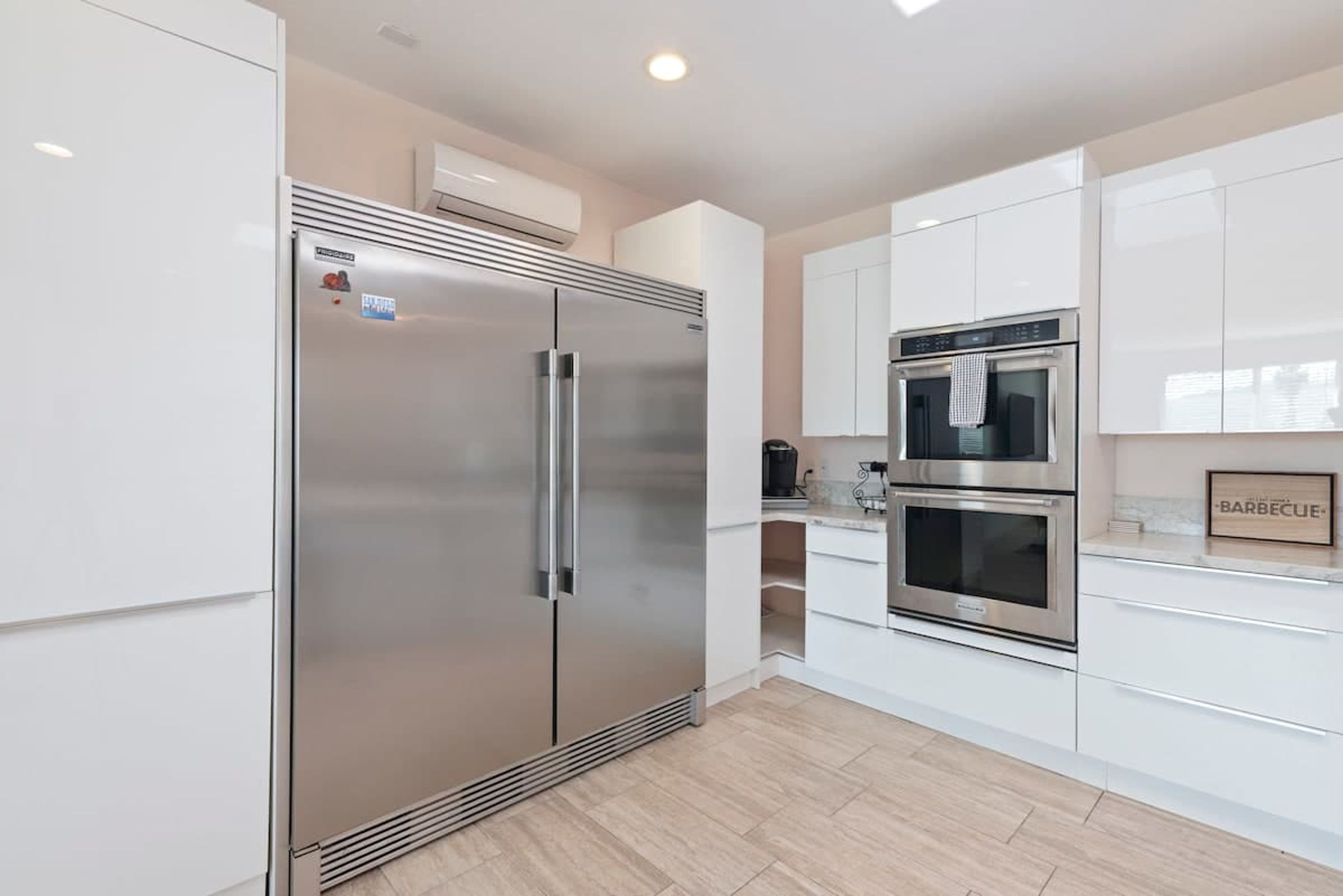 A modern kitchen with stainless steel appliances, white cabinetry, and a built-in oven.