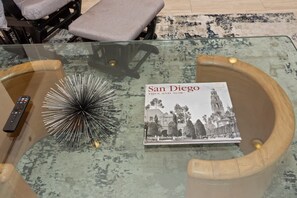A glass coffee table with a book titled "San Diego Then and Now" and a decorative metal piece. - Spacious Single Level Home In Poway (Poway)