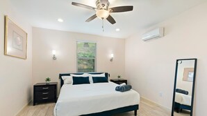 A bedroom with a bed, a ceiling fan, a window, a nightstand, and a mirror. - Spacious Single Level Home In Poway (Poway)