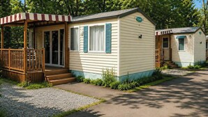 Une maison mobile dotée d’une véranda, de quelques marches et d’une petite terrasse.