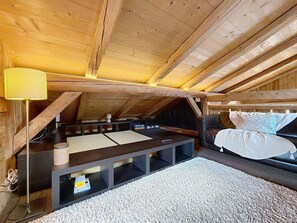A cozy attic bedroom with a bed, a small table, and a lamp. - Chalet with 5 bedrooms + dormitory near Combloux slopes (Combloux)