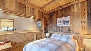 Habitación de cabaña de madera con cama, mesita de noche, espejo e imagen colgada en la pared.