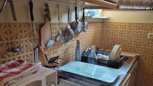 A kitchen with a microwave, a stove, and various utensils hanging above. - 2-Bedroom Apartment with Balcony and Parking in Cauterets (Cauterets)