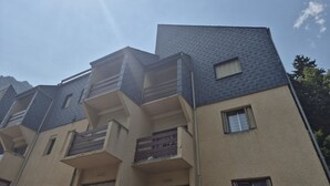 A multi-story building with a sloped roof, balconies, and windows. - 2-Bedroom Apartment with Balcony and Parking in Cauterets (Cauterets)