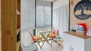 Ein gemütliches Zimmer mit einer Schiebetür und einem kleinen Essbereich mit Tisch und Stühlen, sowie einer Wandablage mit Schild für das WLAN-Passwort.