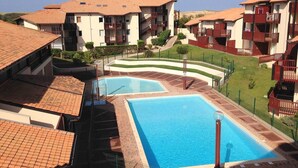Ein Hotel mit Schwimmbad, mehreren Balkonen und einem angelegten Garten.