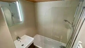 Een badkamer met een douchecabine van glas, een wastafel en een spiegel.