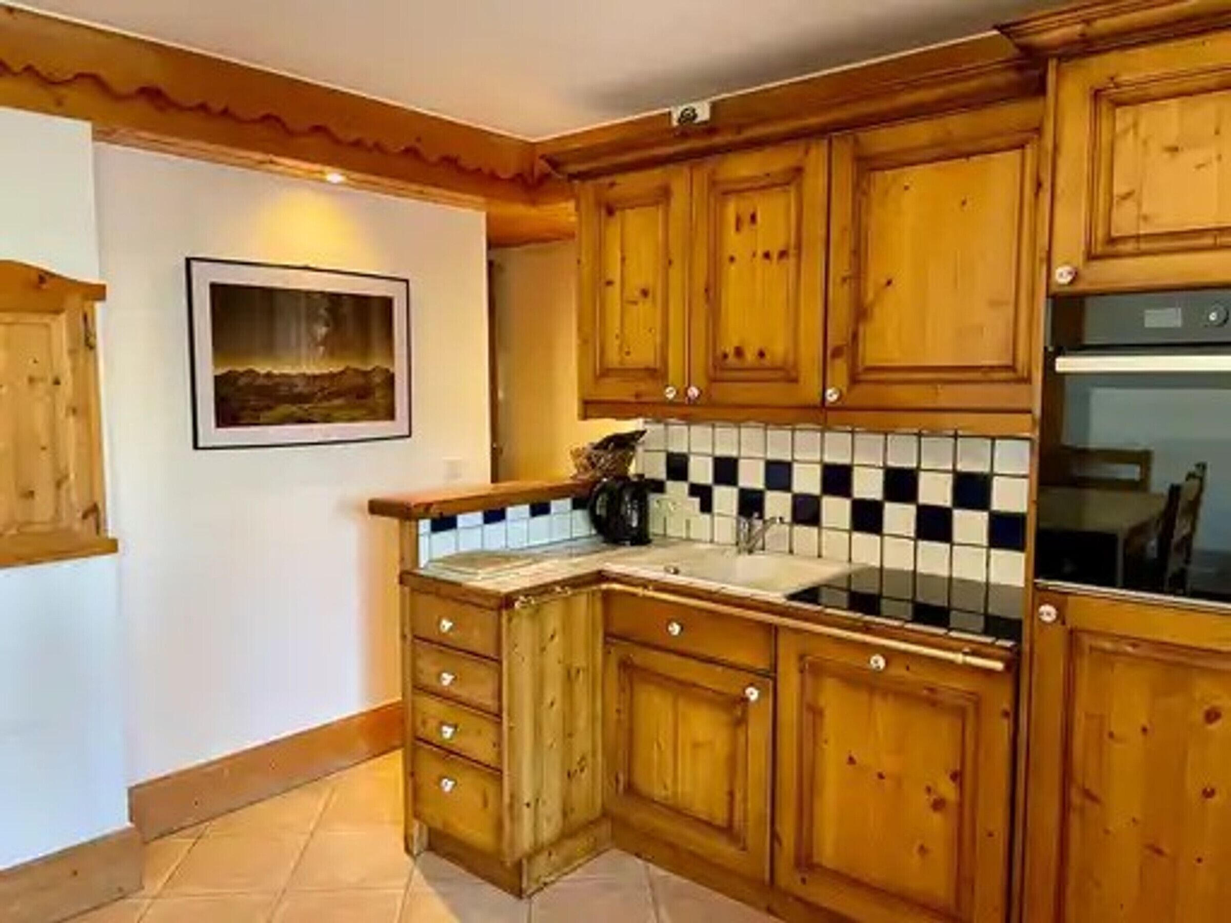 Una cocina con armarios de madera, salpicadero de azulejos y horno empotrado.