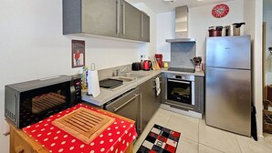 Cocina compacta con microondas, estufa, lavaplatos y refrigerador.