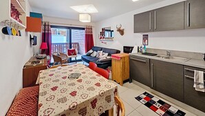 Un espacio habitable compacto con comedor, cocina y puerta de vidrio corredera que da a un área exterior.