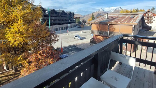 A balcony with a view of a street, buildings, and mountains. - 22m² Studio for 4 near slopes (Les Deux Alpes)