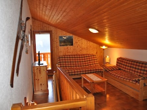 A cozy cabin interior with wooden walls and ceiling, a plaid sofa, a wooden bench, and a small table. - Spacious apartment with south/west-facing balcony and WIFI connection (Châtel)