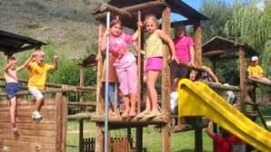 Une structure de jeu en bois, dotée d’un toboggan et d’éléments d’escalade.