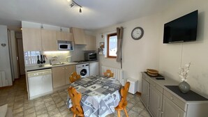 A compact kitchen with a dining area, a microwave, a washing machine, and a flat-screen TV. - Quiet apartment near the center with balcony and garage in Châtel (Châtel)