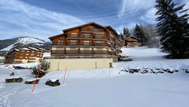 A multi-story hotel with balconies, set in a snowy mountainous area. - Quiet apartment near the center with balcony and garage in Châtel (Châtel)