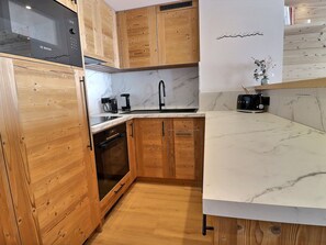 A kitchen with wooden cabinets, a Bosch microwave, a sink, a coffee maker, and a toaster. - Stunning 4-room apartment, ski-in/ski-out, renovated, 6-7 pers., south (Méribel)
