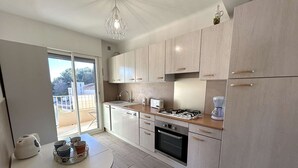 Une cuisine moderne avec des meubles de couleur bois clair, une cuisinière à gaz, un four encastré et une machine à café.