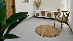 A modern, minimalist room with a wooden door, a white console table, a woven rug, and a wooden chair. - Dreamy homestay Hue (Hue)