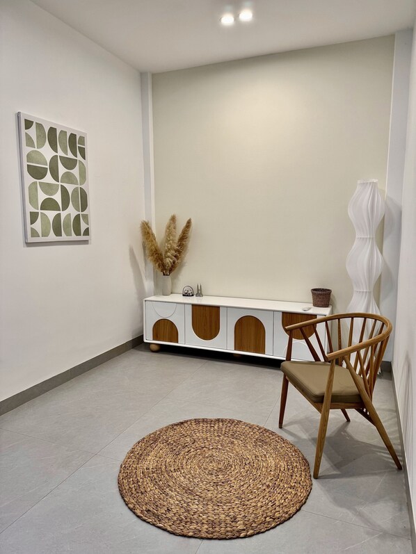 Une pièce moderne avec une console blanche, un tapis tissé et une chaise en bois.