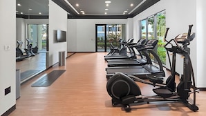 A modern gym with multiple treadmills, stationary bikes, and a large mirror. - 1BR Creek Beach Access (Dubai)